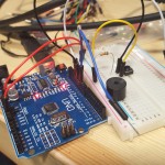 Photo of an arduino uno with a breadboard, jumper cables, switch and buzzer.