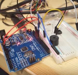 Photo of an arduino uno with a breadboard, jumper cables, switch and buzzer.