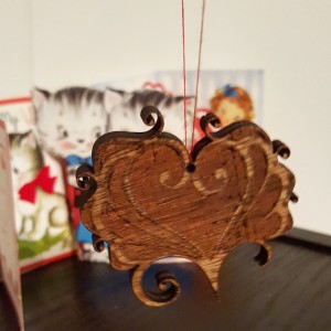 A photo of a wooden laser cut heart valentine on a thread. 