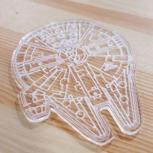 A photo of a millennium falcon laser cut out of clear acrylic. 